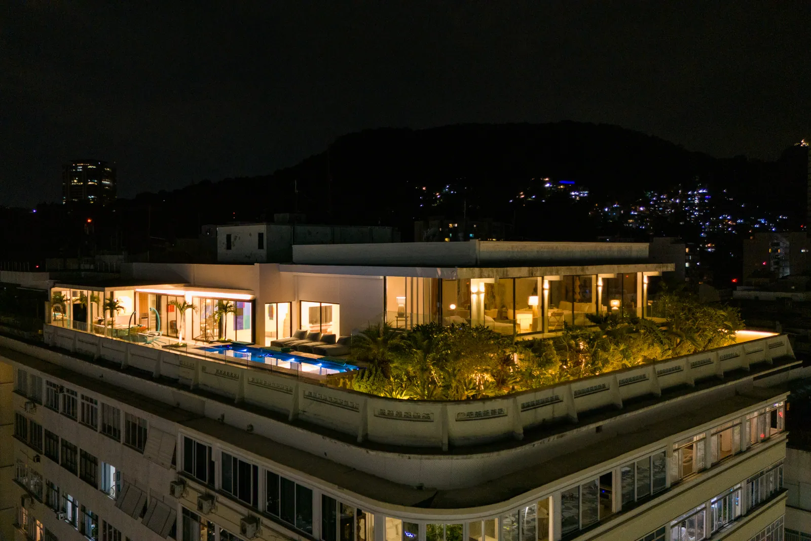 The penthouse lit at night, a crown along the roof of the building