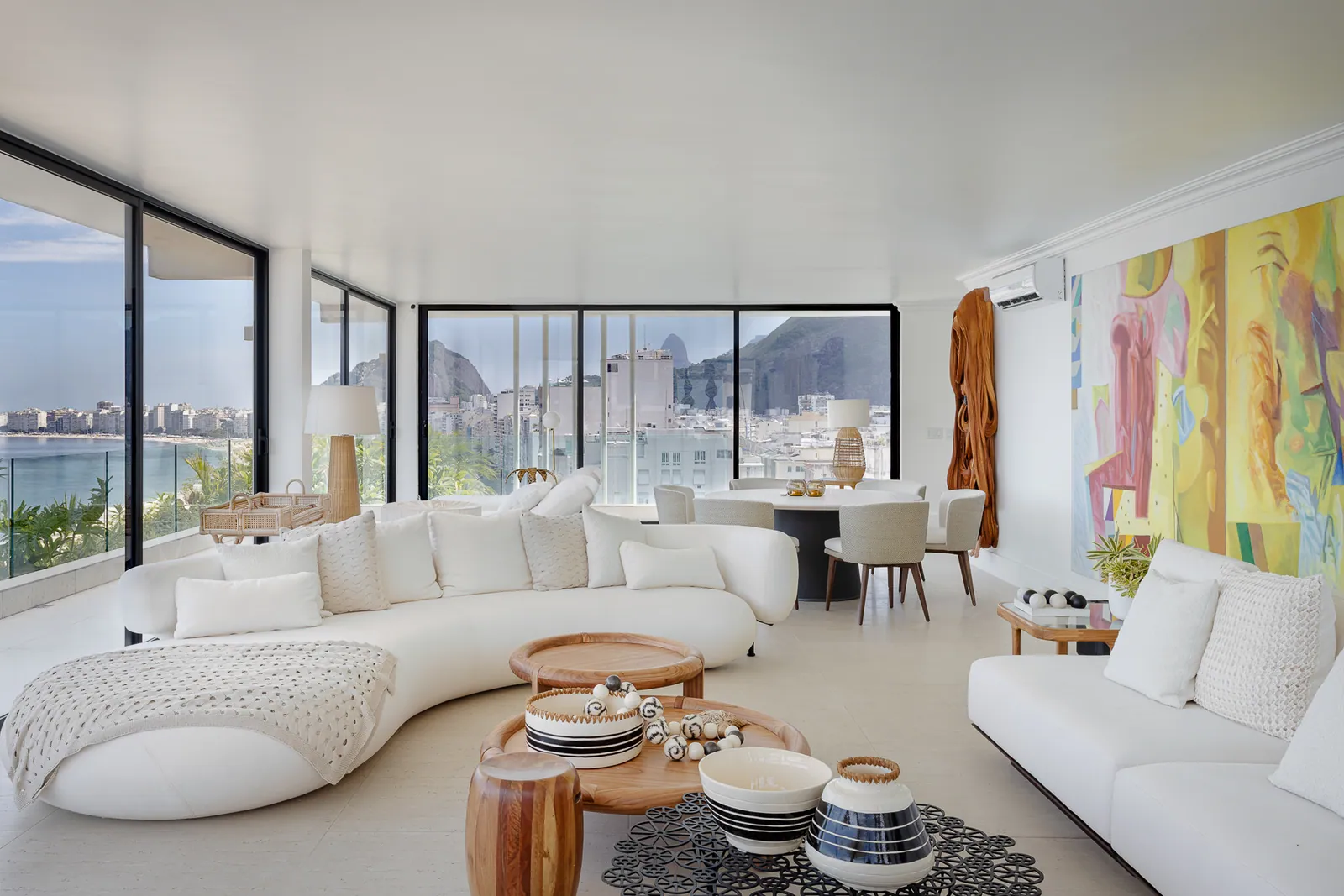 Curved white sofas in the living room, glass opening onto Copacabana