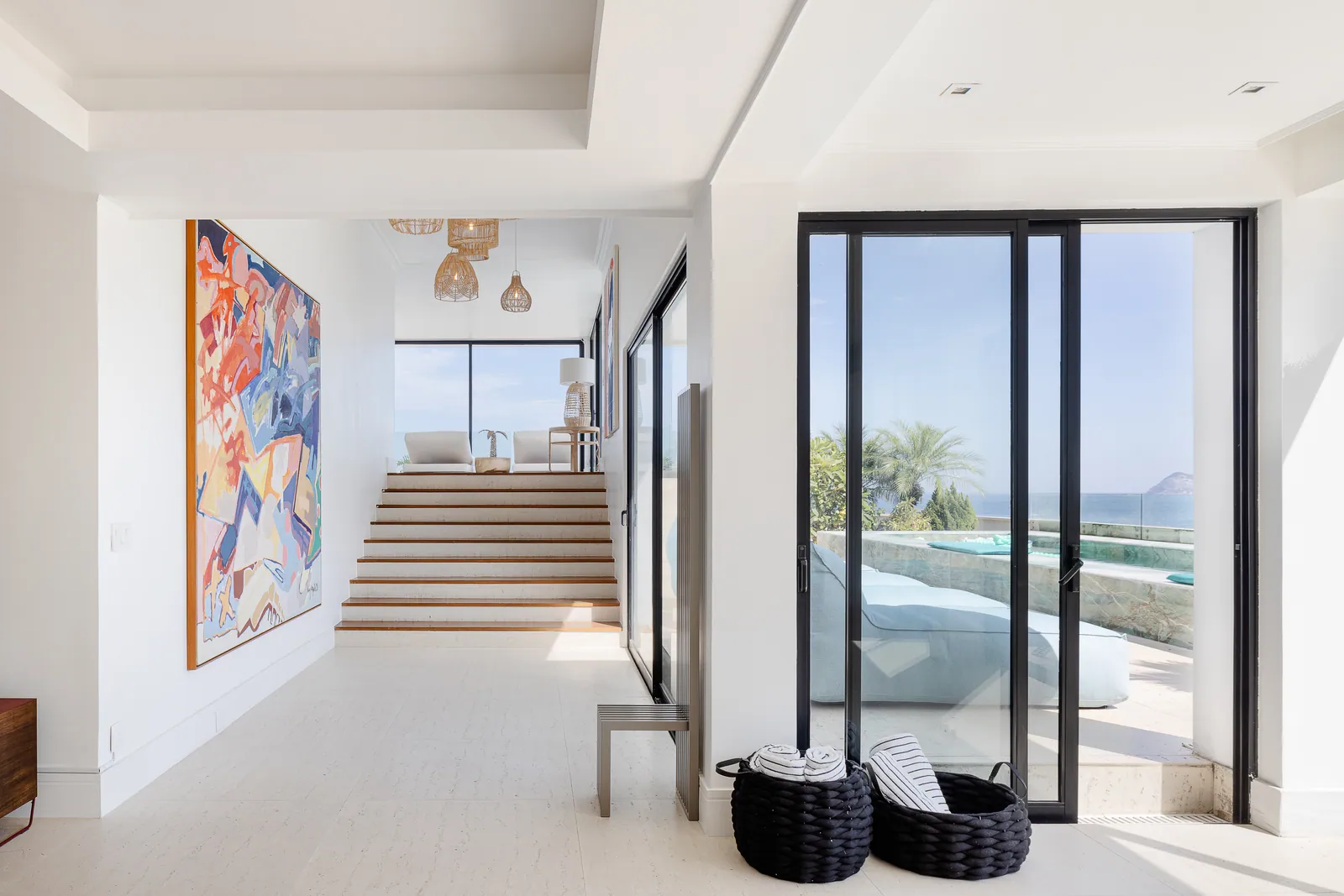 Entrance hall and steps, artwork on the wall, pool beyond the glass