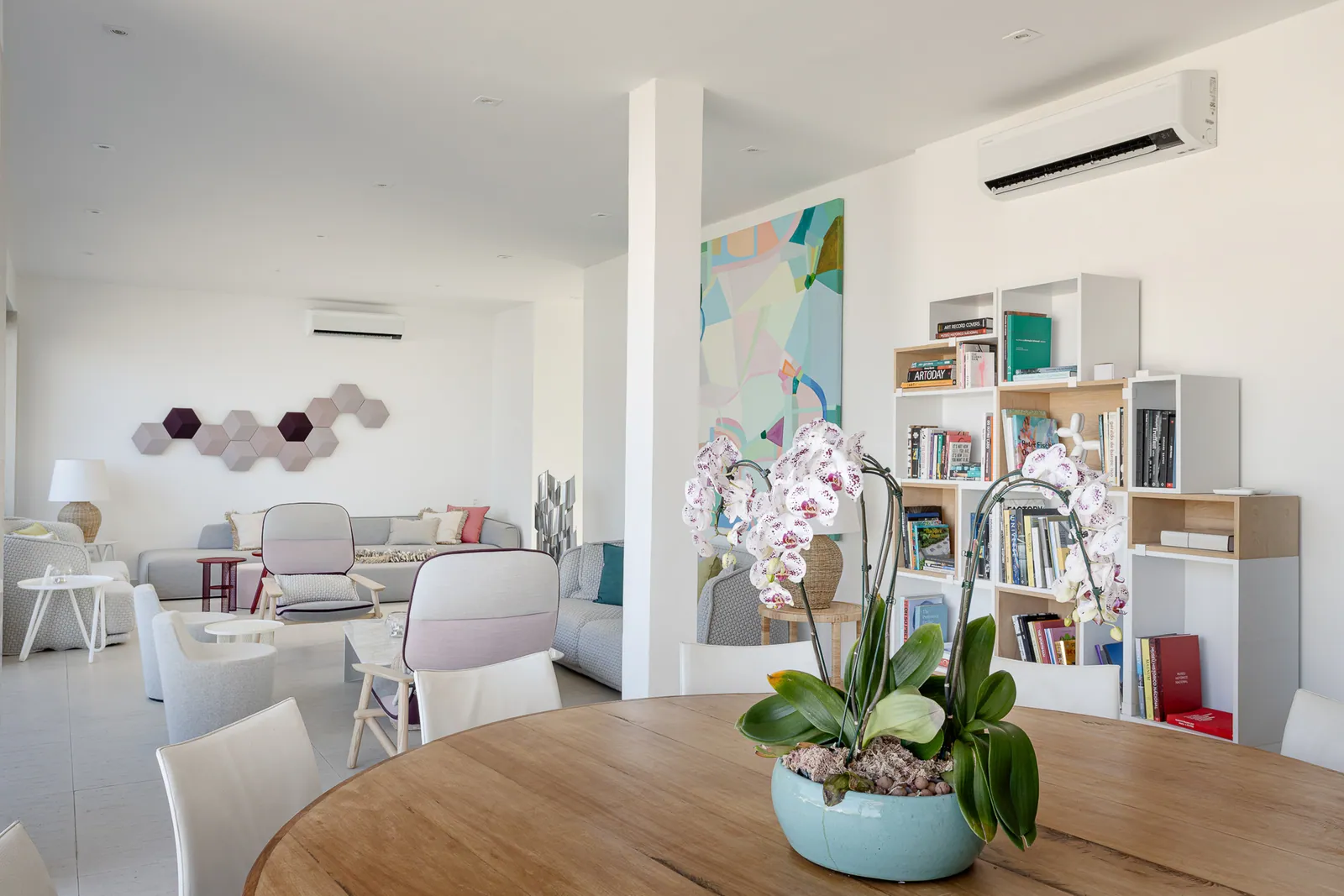 Open living and dining area with bookshelves and orchids