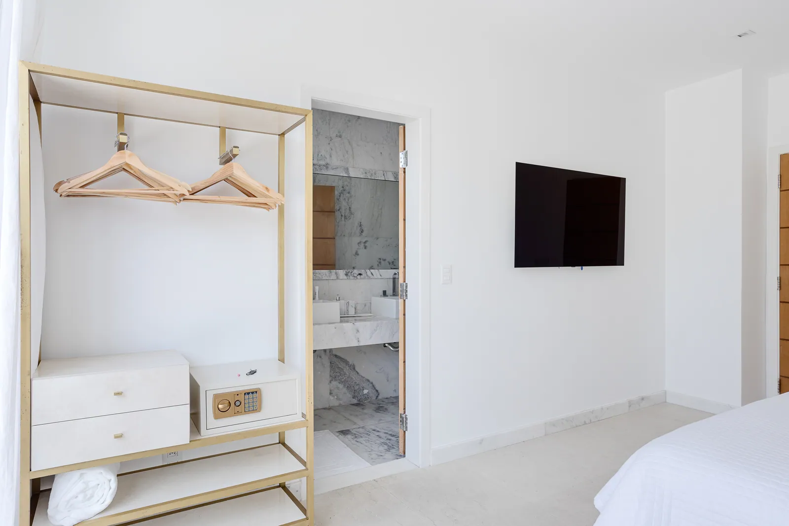 Bedroom with open wardrobe, safe and marble bathroom beyond