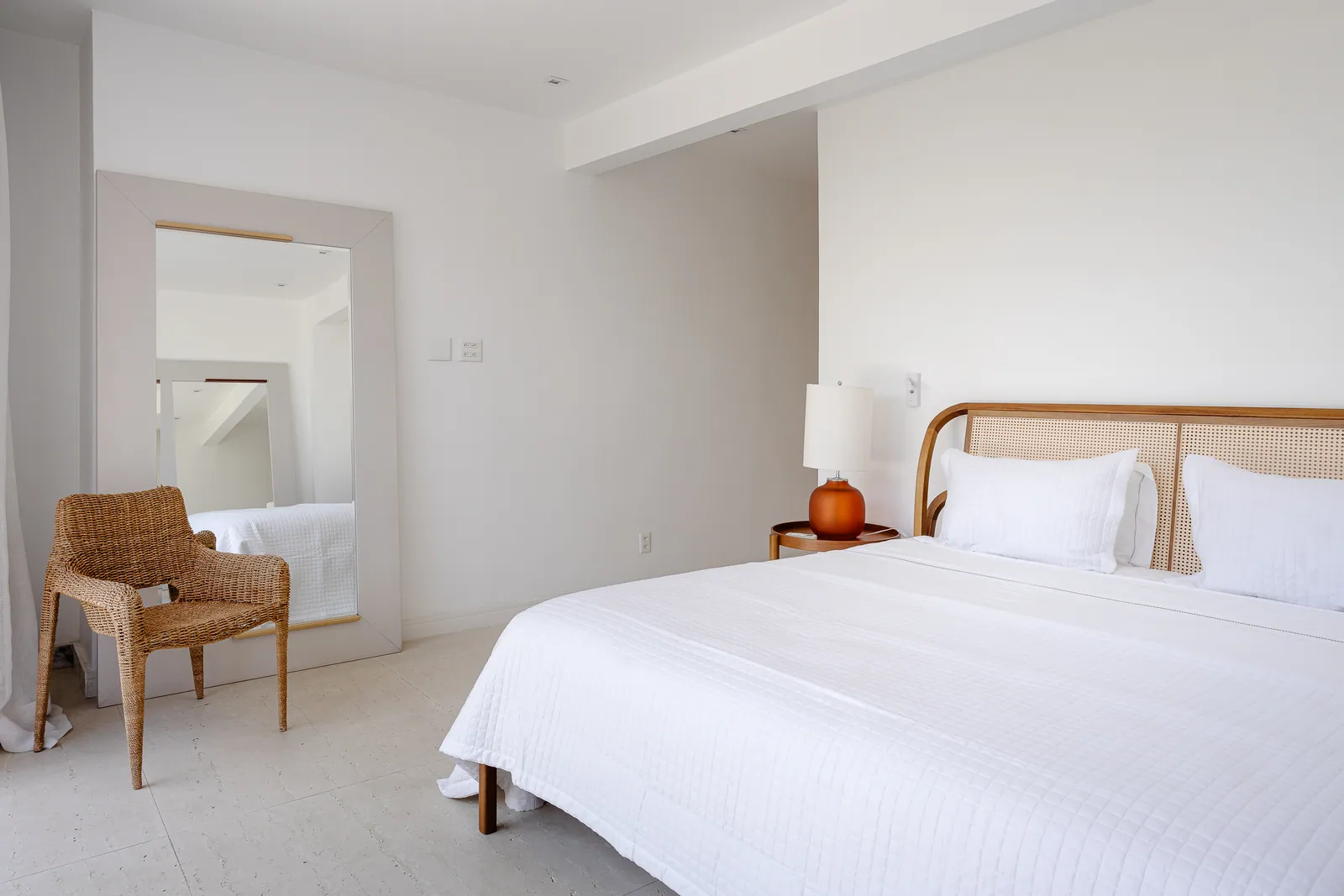 Bedroom with rattan armchair and wood headboard