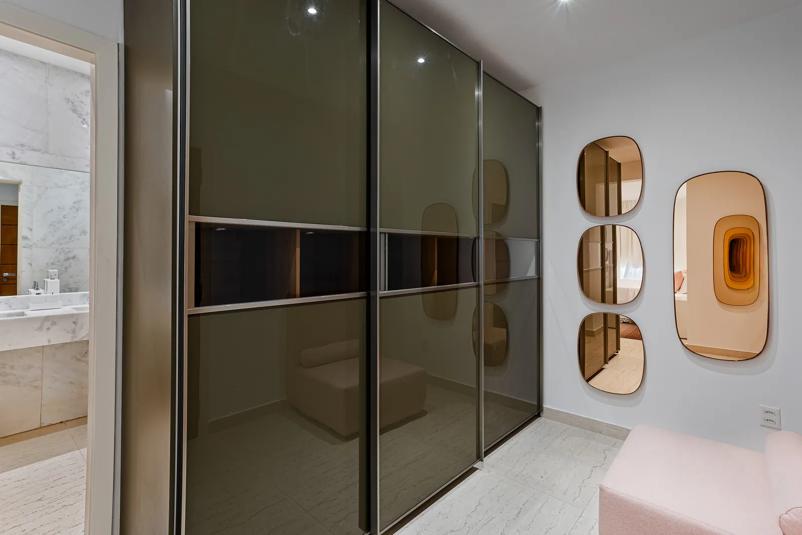 Dressing room with smoked glass wardrobe, bathroom beyond