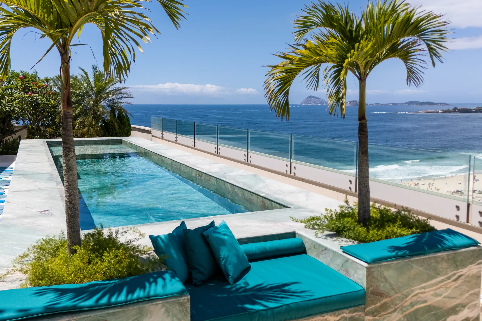 Heated infinity pool framed by two tall palms, the Atlantic beyond