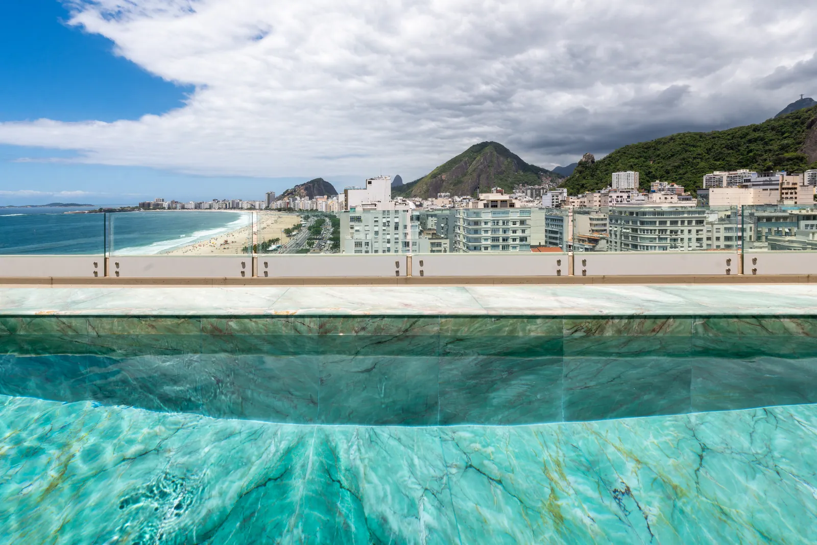 Water's edge of the infinity pool, the beach curving away below