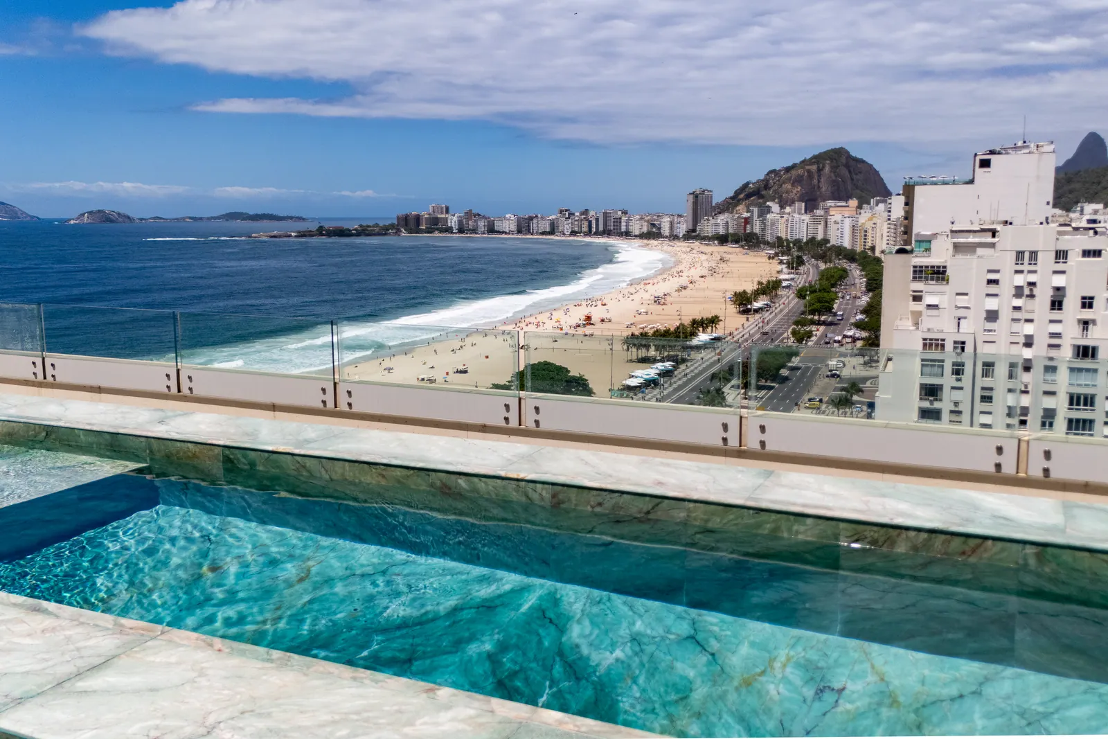 Marble pool deck with the beach and the hills of Rio behind