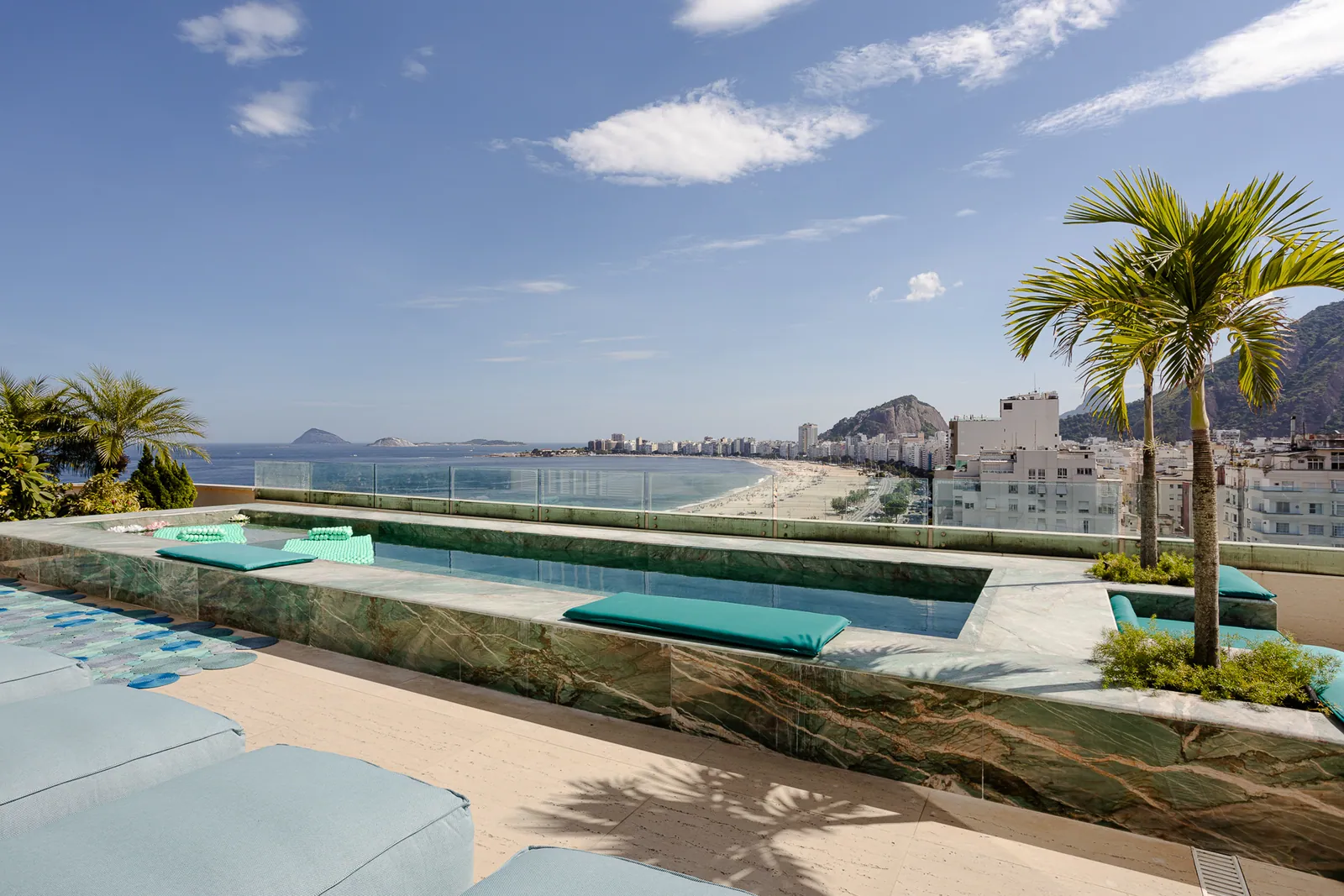 Palms and cushioned seating along the length of the pool