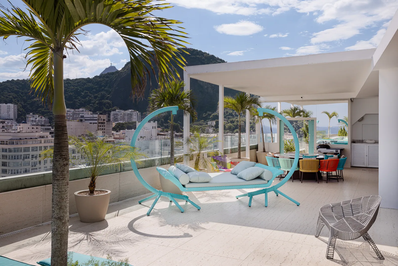 Hanging chairs and lounge seating on the terrace, hills behind