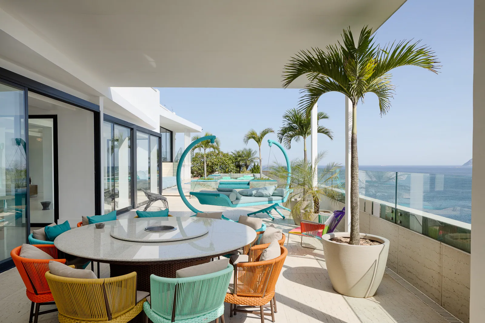 Round outdoor dining table under a palm, ocean beyond